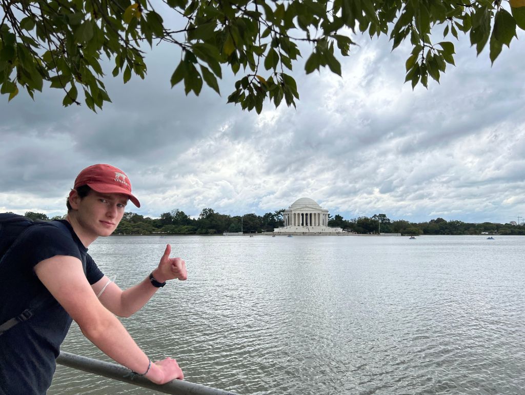 Image of Owen A. thumbs-uping the U.S. Capitol from across the Capitol Reflecting Pool.