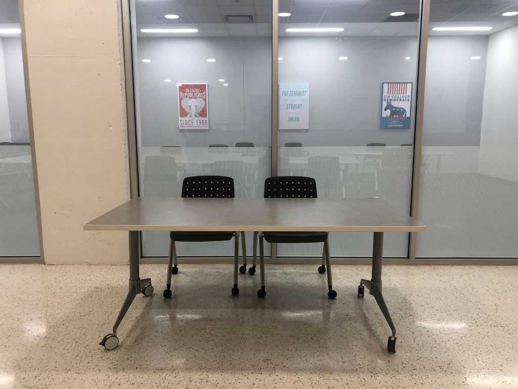 Rectangular tabling space table on wheels with two chairs behind it