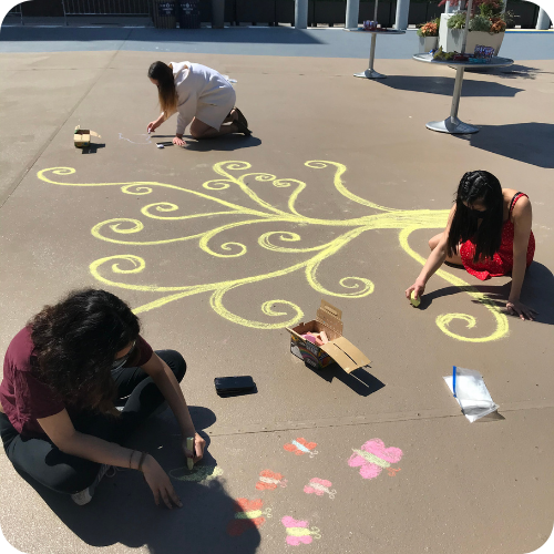 3 students drawing with chalk in potomac square