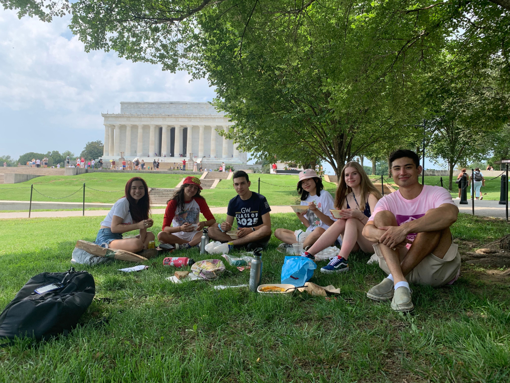 Six people eating lunch on the National Mall with the Lincoln Memorial in the background