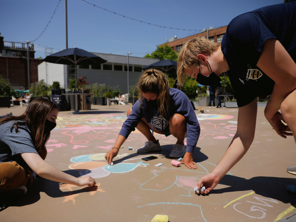 Three students draw with chalk on Potomac Square during the 40th Annual Chalk-In in April 2021.